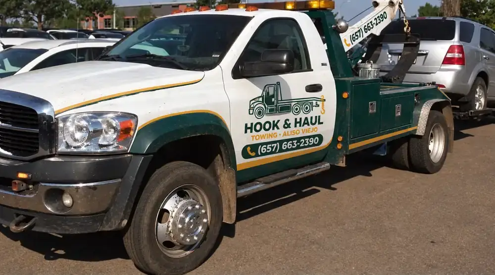 Green and white Hook & Haul tow truck parked in Aliso Viejo